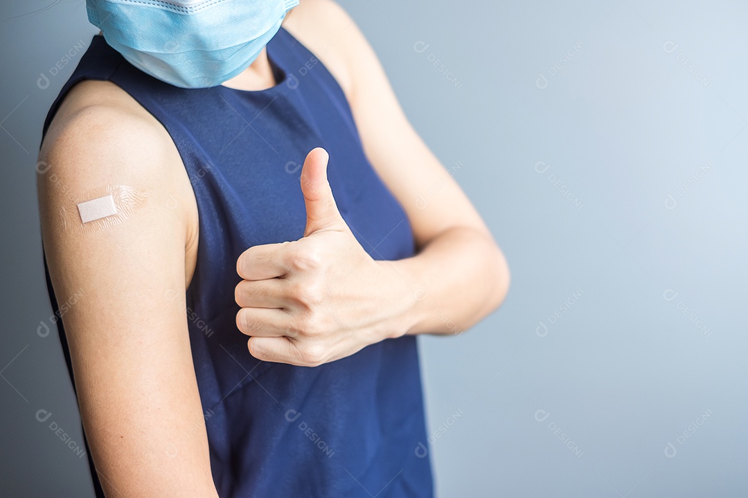 Mulher feliz mostrando o polegar com curativo depois de receber o covid 19