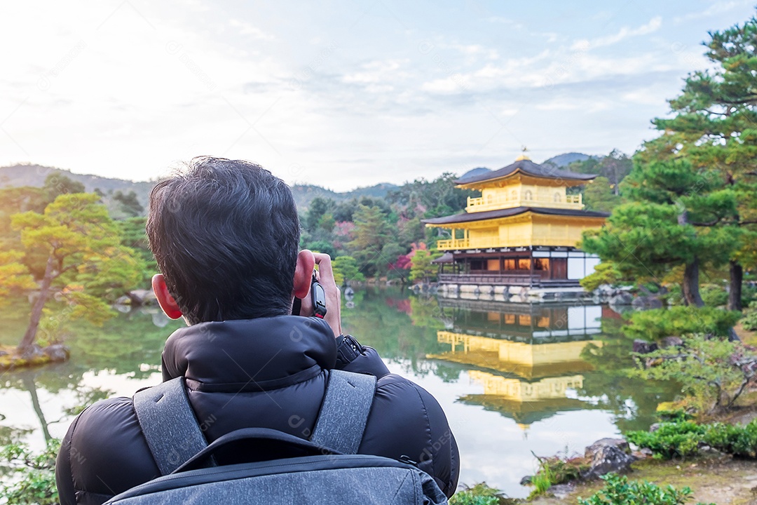 Turista de homem solo tirando foto pela câmera no templo Kinkakuji ou no pavilhão dourado na temporada de outono, visita de viajante asiático em Kyoto, Japão. Conceito de férias, destino e viagens