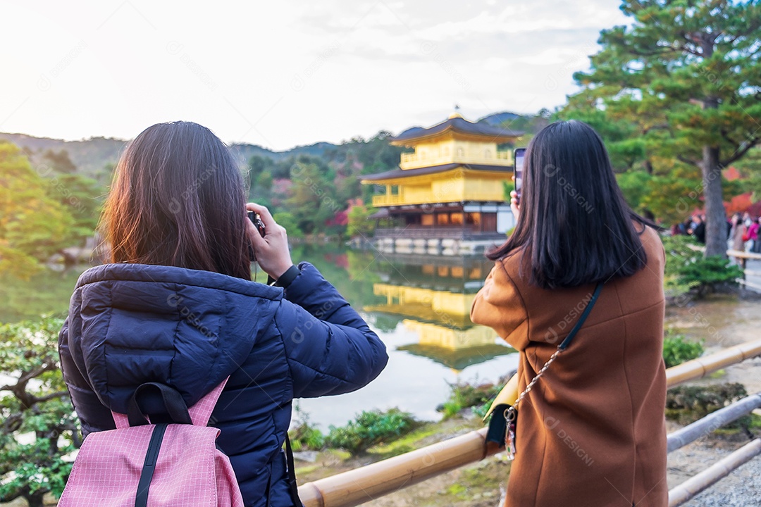 Turista mulher tirando foto pela câmera no templo Kinkakuji ou no pavilhão dourado na temporada de outono, visita de viajante asiático em Kyoto, Japão. Conceito de férias, destino e viagens