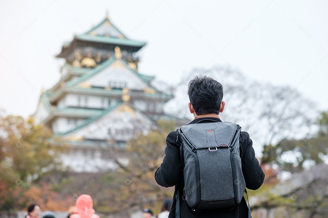 Turista solo viajando no castelo de Osaka na temporada de outono, visita de viajante asiático na cidade de Osaka, Japão. Conceito de férias, destino e viagens