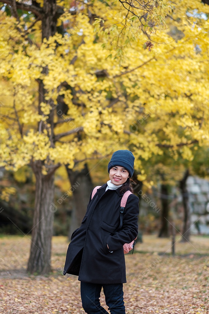 Homem feliz desfruta no parque ao ar livre na temporada de outono, viajante asiático de casaco e câmera contra o fundo Yellow Ginkgo Leaves