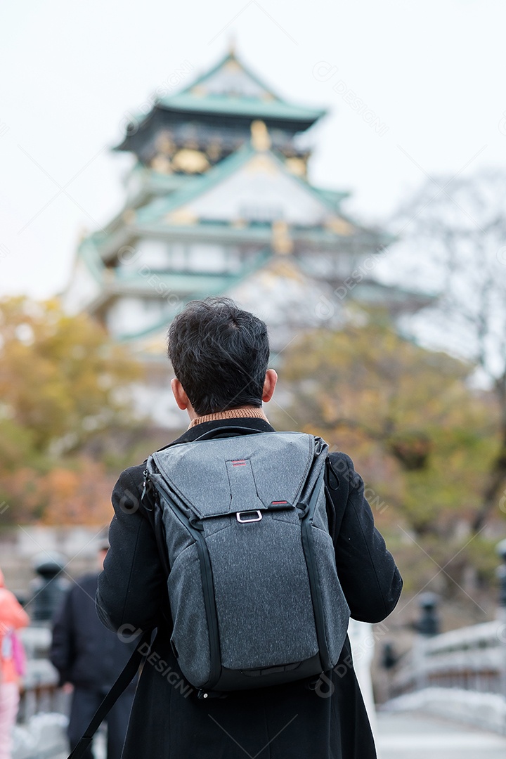 Turista solo viajando no castelo de Osaka na temporada de outono, visita de viajante asiático na cidade de Osaka, Japão. Conceito de férias, destino e viagens