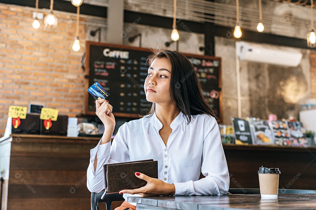 Aceitar cartões de crédito de uma bolsa marrom para pagar mercadorias em pedidos de café.