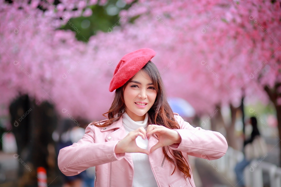 Uma mulher viajante hipster passear usa um chapéu vermelho com uma bela árvore de flores de cerejeira sakura desabrochando na cor rosa no parque em um dia de primavera.