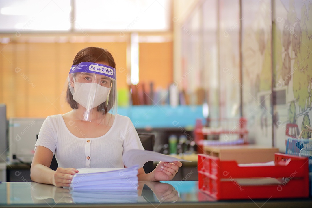 Mulher trabalhadora de escritório usando protetor facial. em quarentena para coronavírus