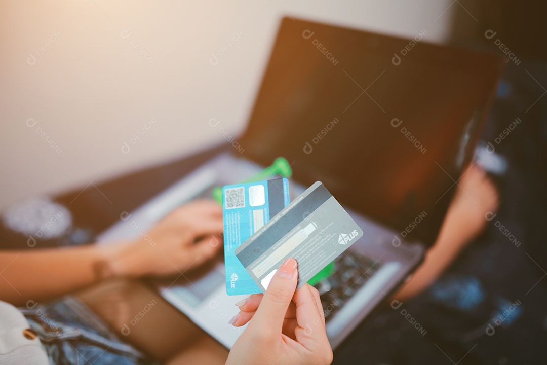 Jovem detém cartões de crédito em um carrinho de compras em casa.