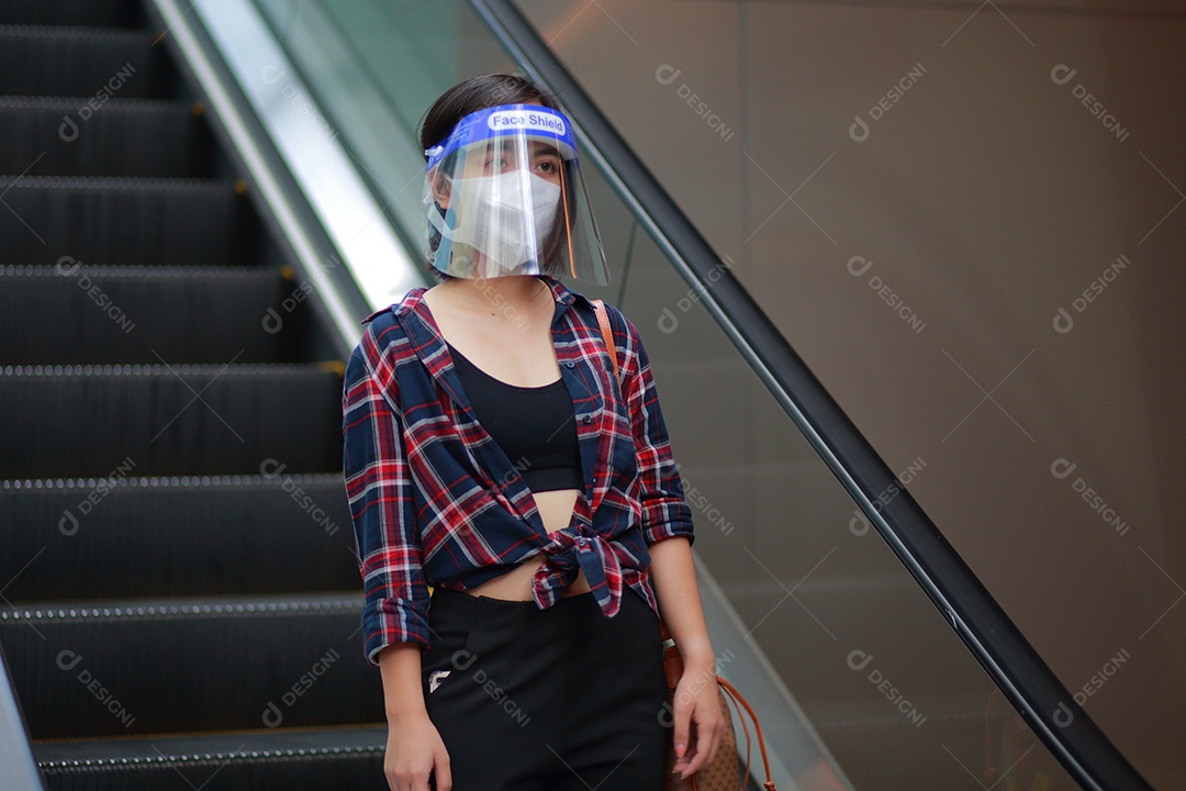 Mulher asiática em escudo facial, máscara facial médica desce a escalada