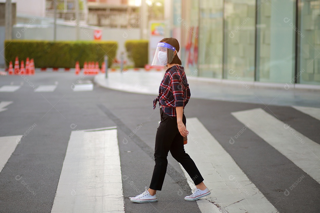 Mulher asiática em escudo facial, máscara facial médica caminha cruzando