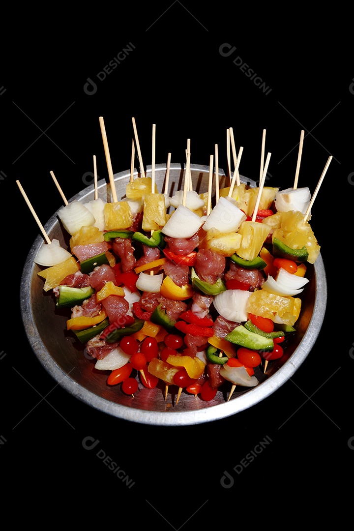 Kebab cru de carne em um fundo de madeira com legumes.