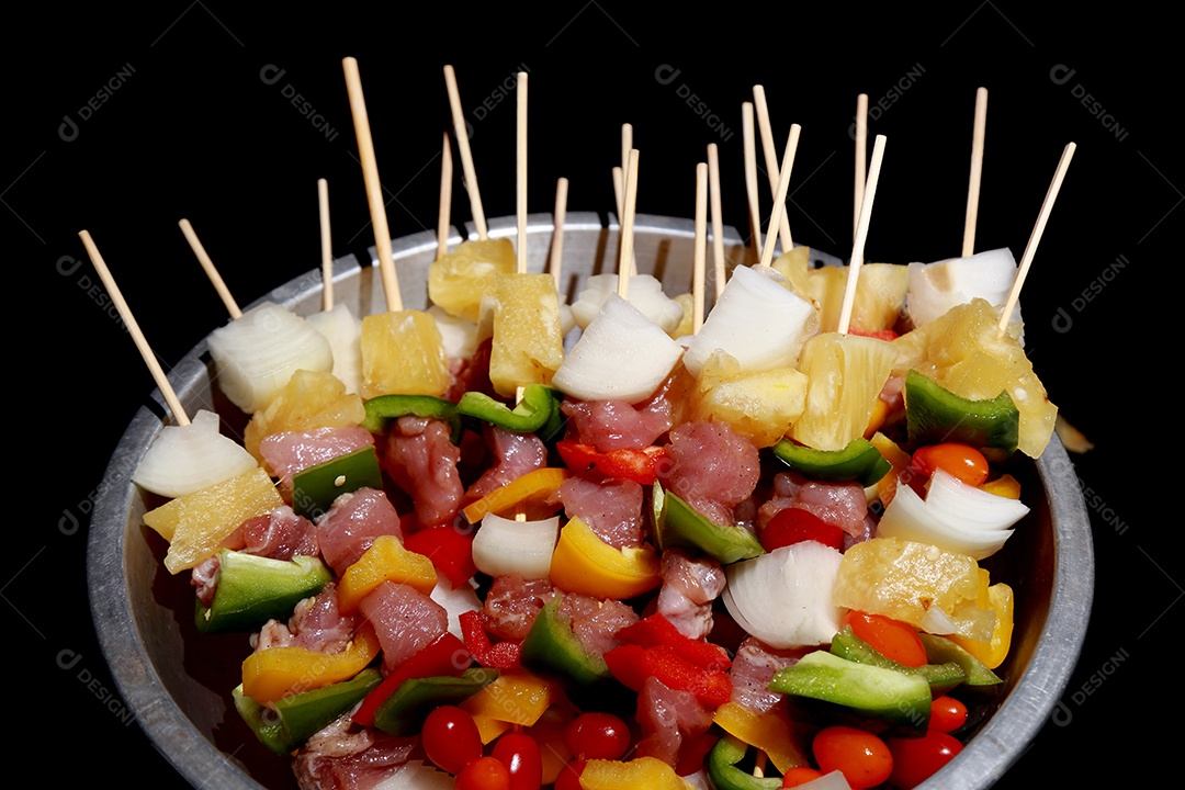 Kebab cru de carne em um fundo de madeira com legumes.