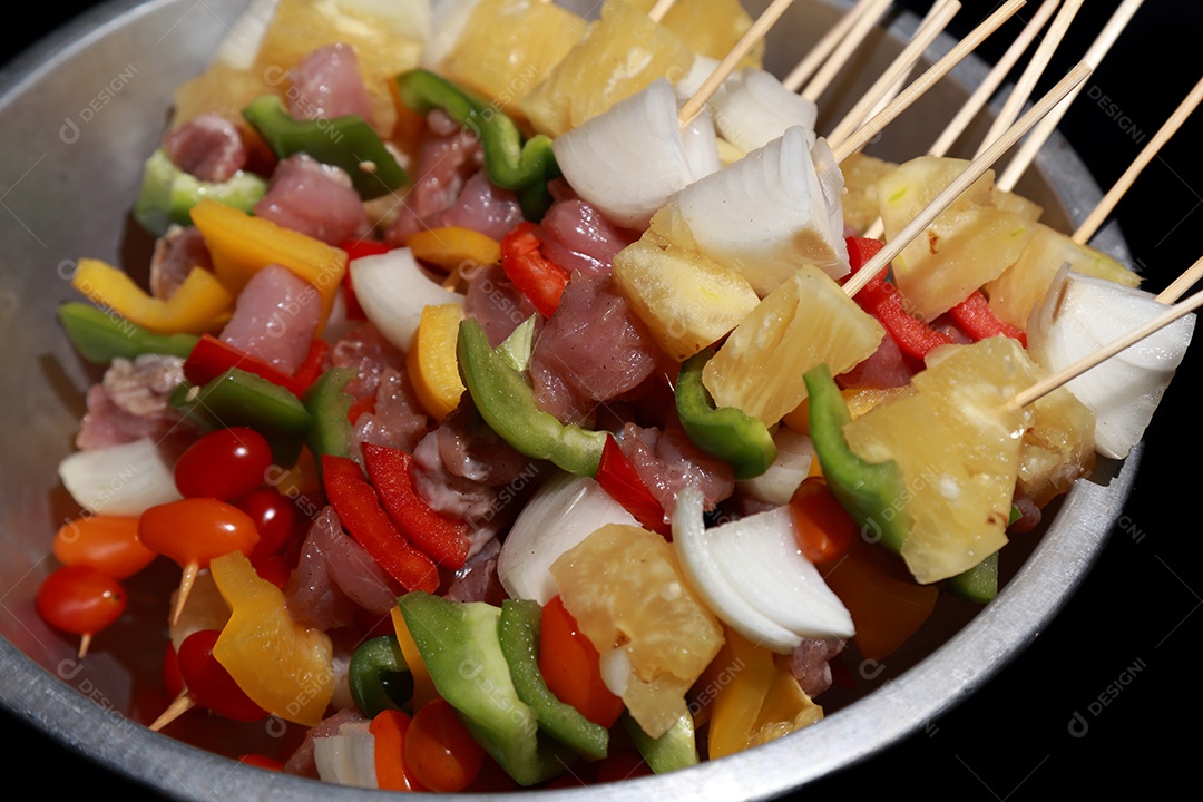 Kebab cru de carne em um fundo de madeira com legumes.