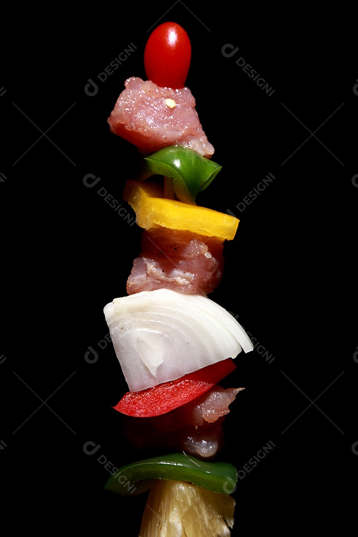 Kebab cru de carne em um fundo de madeira com legumes.