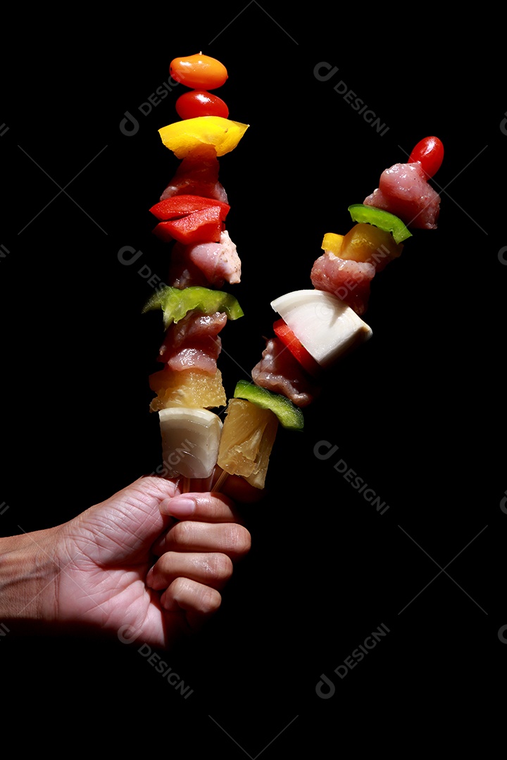 Kebab cru de carne em um fundo de madeira com legumes.