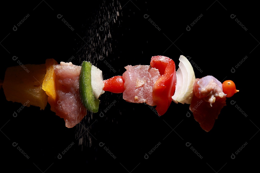 Kebab cru de carne em um fundo de madeira com legumes e polvilhado com pimenta em pó.