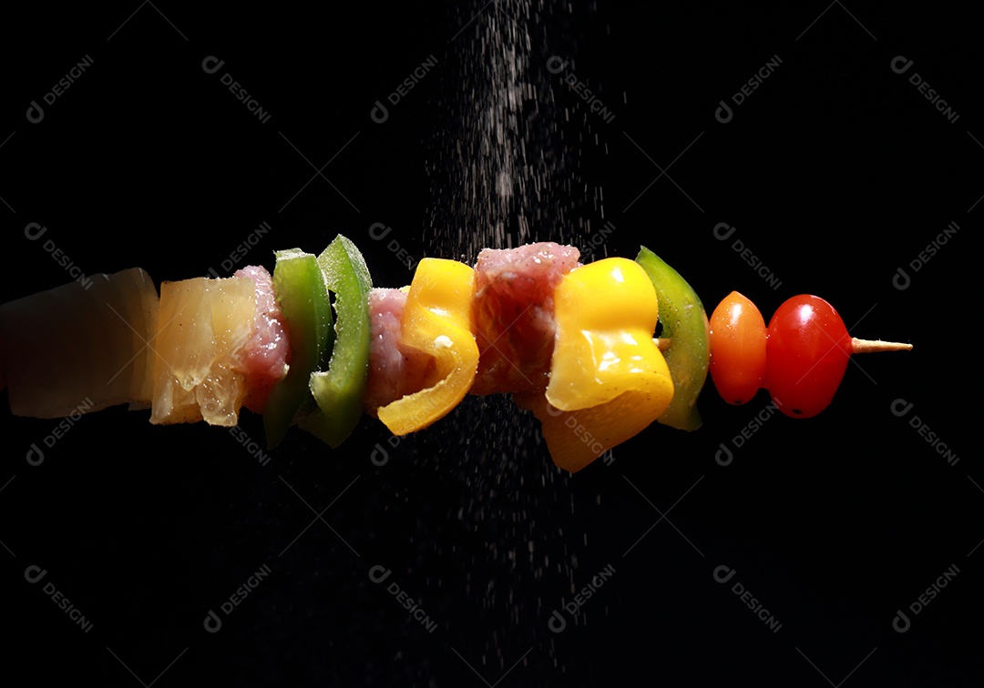 Kebab cru de carne em um fundo de madeira com legumes e polvilhado com pimenta em pó.