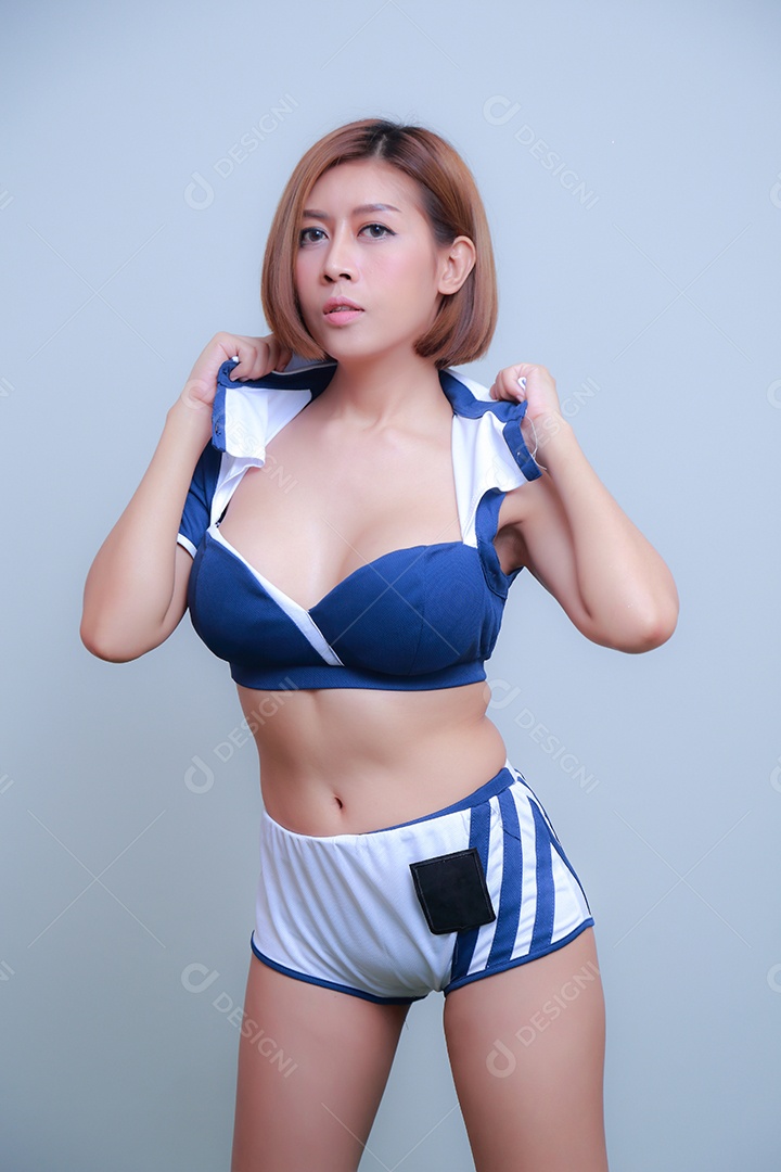 Linda e sexy líder de torcida posando de mulher vestida com roupas esportivas, jogando futebol em fundo branco.