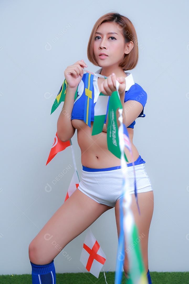 Linda e sexy líder de torcida posando de mulher vestida com roupas esportivas, jogando futebol em fundo branco.