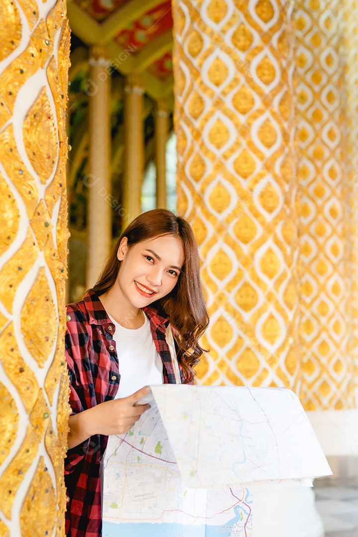 Retrato jovem mochileiro asiático em pé de máscara e segurar o mapa de papel na mão no belo templo tailandês, ela procurando direção