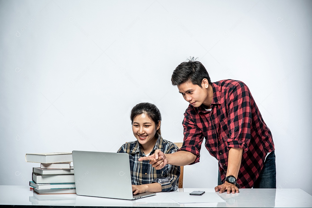 Mulher ensinam os homens a trabalhar com laptops no trabalho.