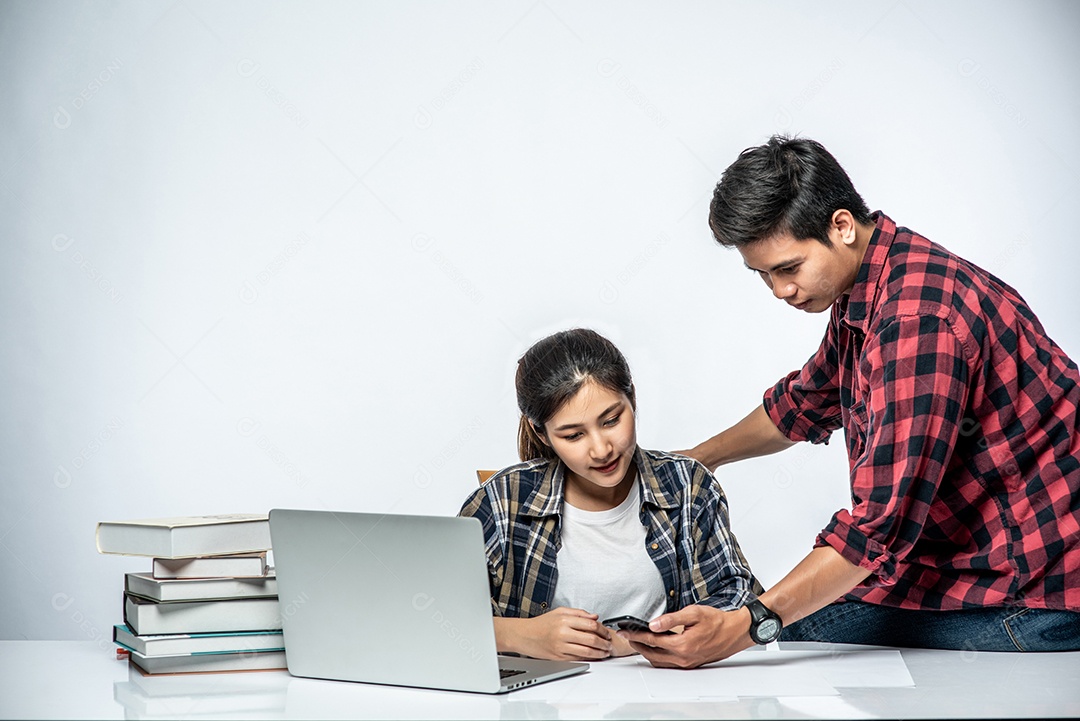 Mulher ensinam os homens a trabalhar com laptops no trabalho.