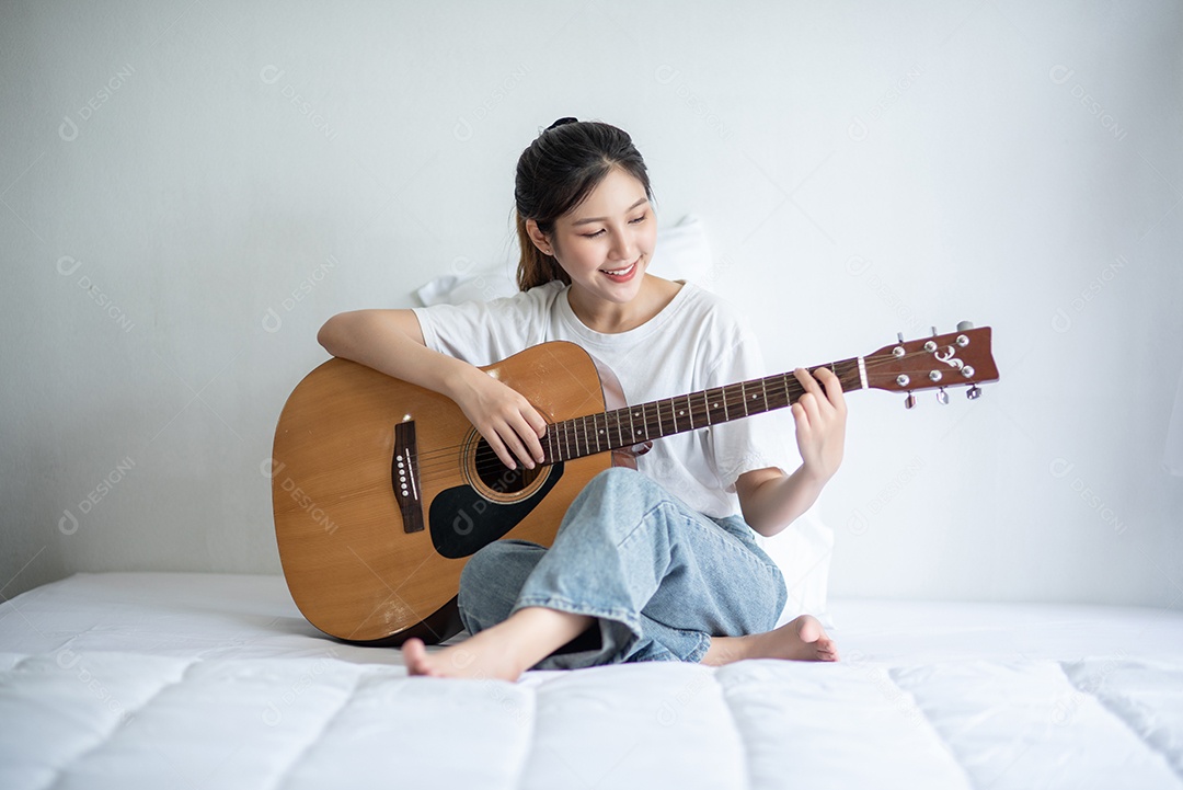 Menina sentou e tocou violão na cama.