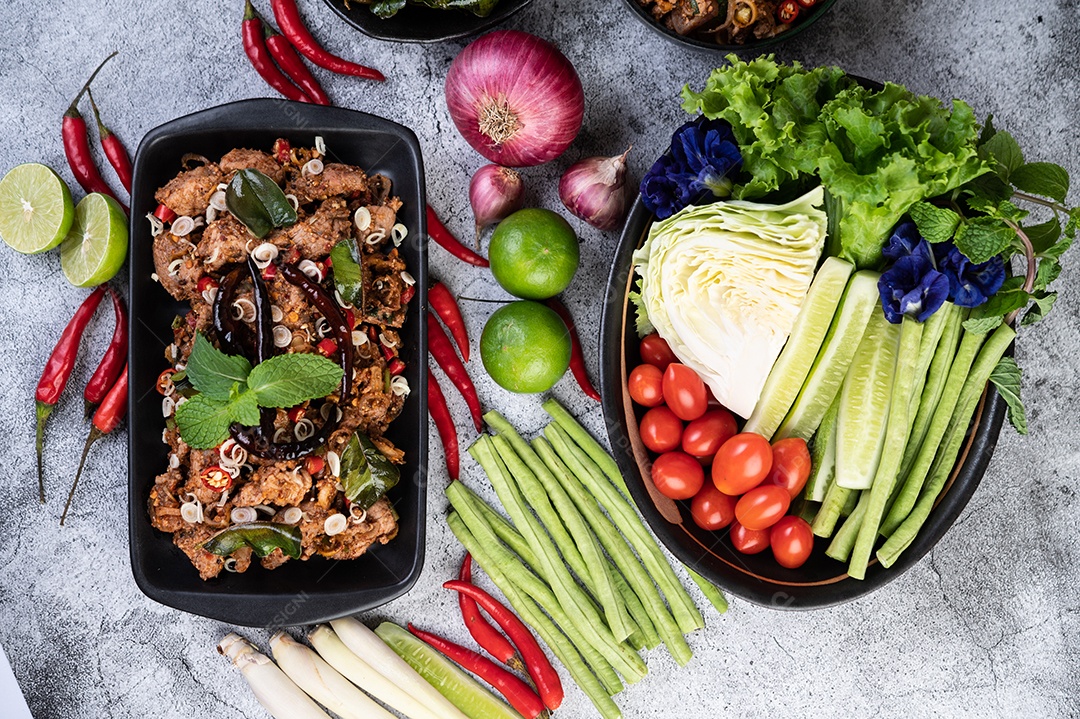 Costeletas de porco picantes em um prato preto composto por limões Chili e acompanhamentos