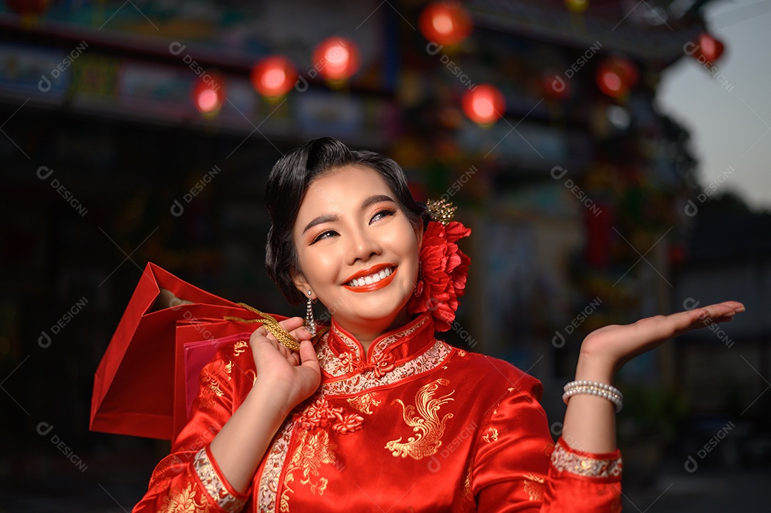 Cena noturna, retrato de mulher bonita asiática vestindo um cheongsam sorrindo e posa com sacolas de compras no santuário no ano novo chinês