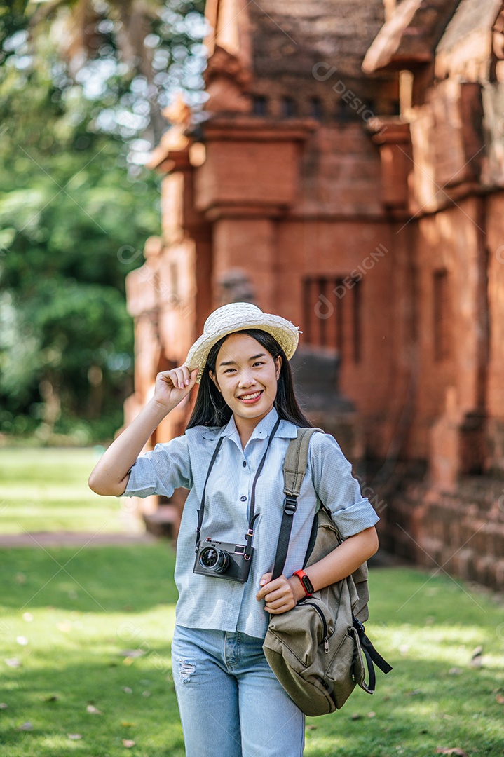 Retrato jovem mochileiro feminino usando chapéu viajando no local antigo, ela usa a câmera para tirar foto com felicidade
