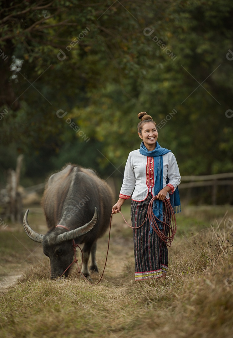woman walks holding buffalo rope in meadow.