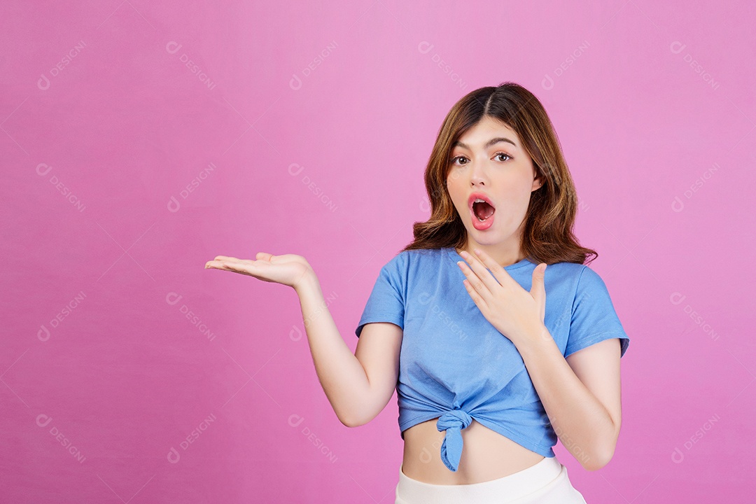 Retrato de jovem animado vestindo camiseta casual segurar a mão demonstrar promo de anúncios de oferta isolado sobre fundo rosa. Expressão, pessoas e conceito de estilo de vida.