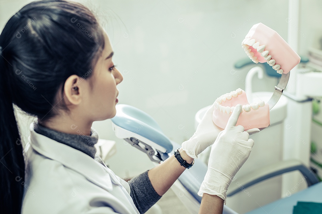 Dentista feminina explicando dentes artificiais ao paciente na clínica