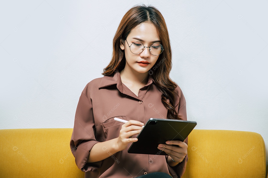 Jovem mulher usando óculos usando tecnologia de caneta digital no tablet para trabalhar em casa durante o auto-isolamento e quarentena surto de coronavírus covid-19