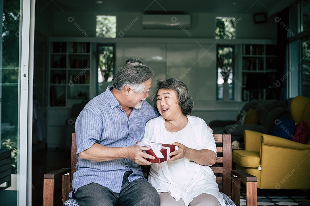 Marido sênior sorridente fazendo surpresa dando caixa de presente para sua esposa