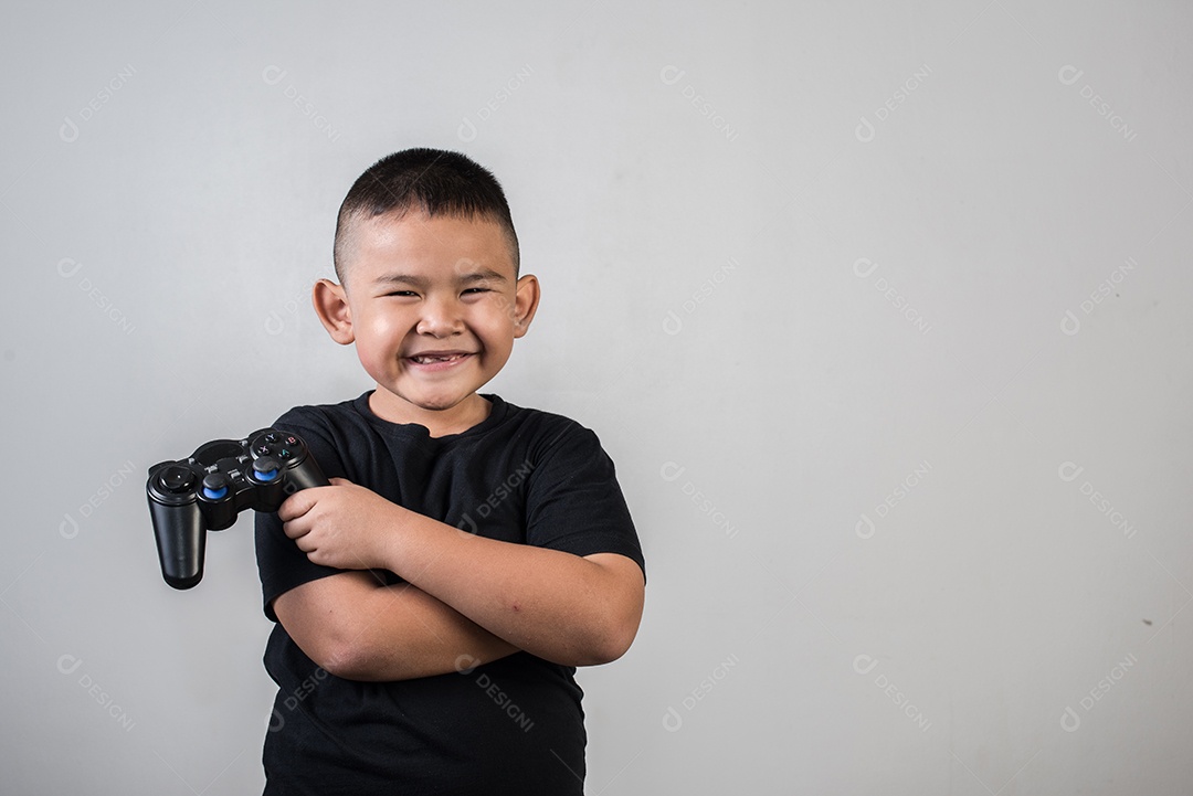 Garoto feliz joga computador de jogo com um controlador em foto de estúdio