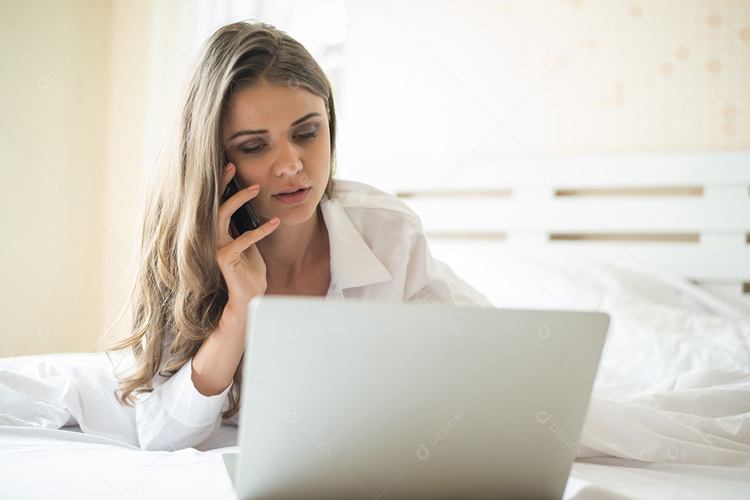 Mulher bonita feliz trabalhando em um laptop na cama em casa