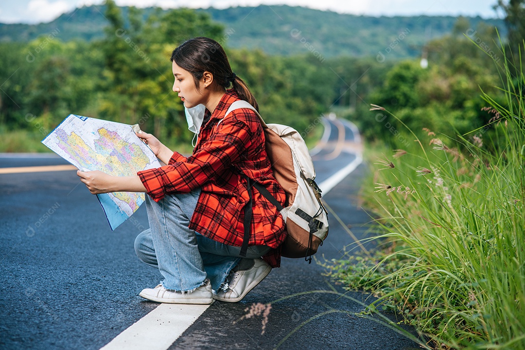 Turistas femininas sentam e olham para o mapa na estrada.