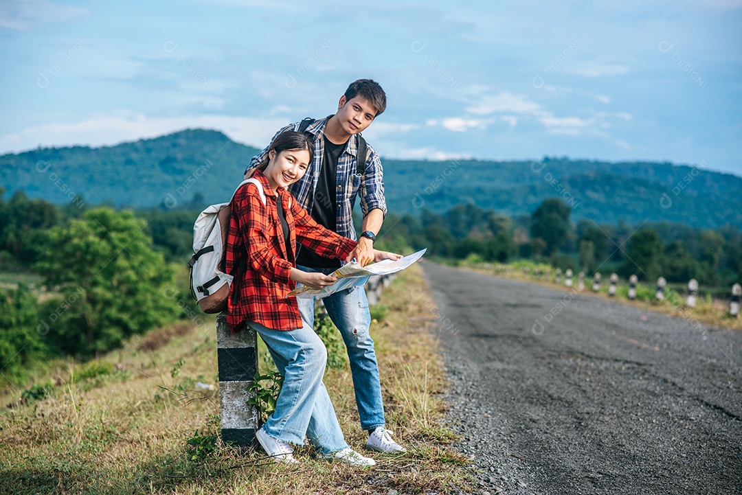 Turistas masculinos e femininos em pé olham para o mapa na estrada.