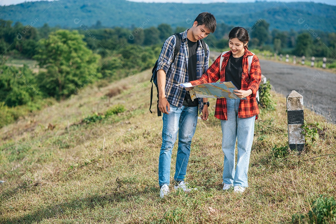 Turistas masculinos e femininos em pé olham para o mapa na estrada.