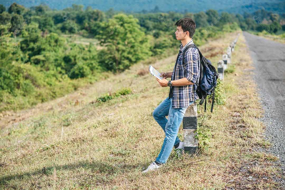 Viajante masculino com uma mochila segurando um mapa e perto de um quilômetro.