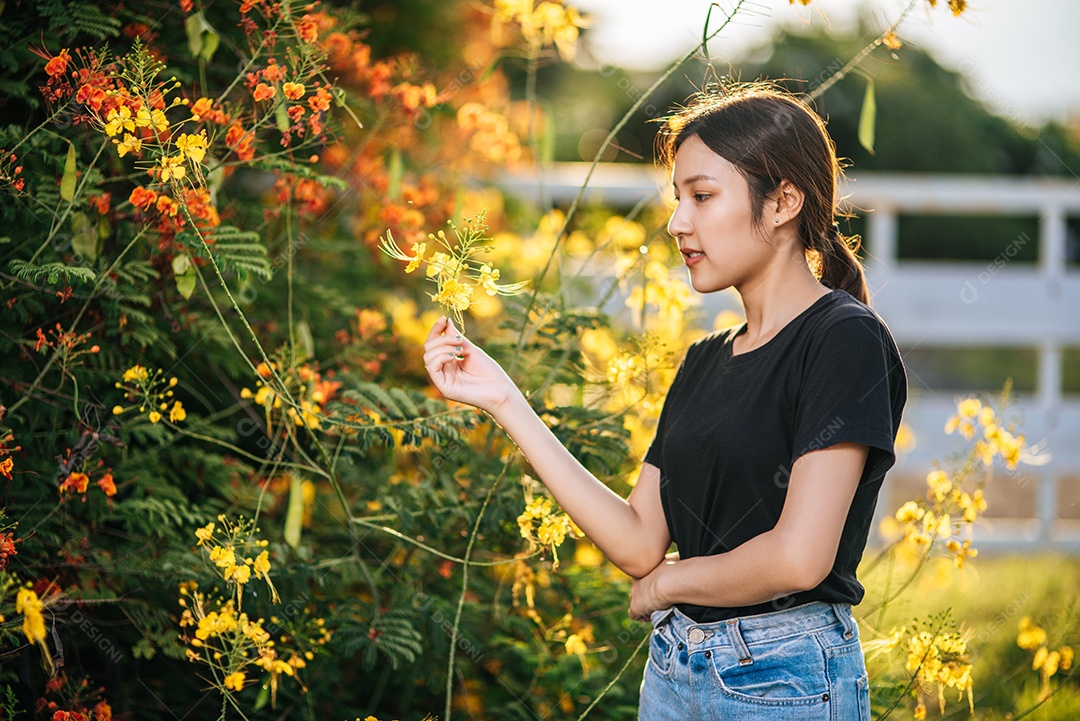 Turistas do sexo feminino ficam e pegam flores no jardim.