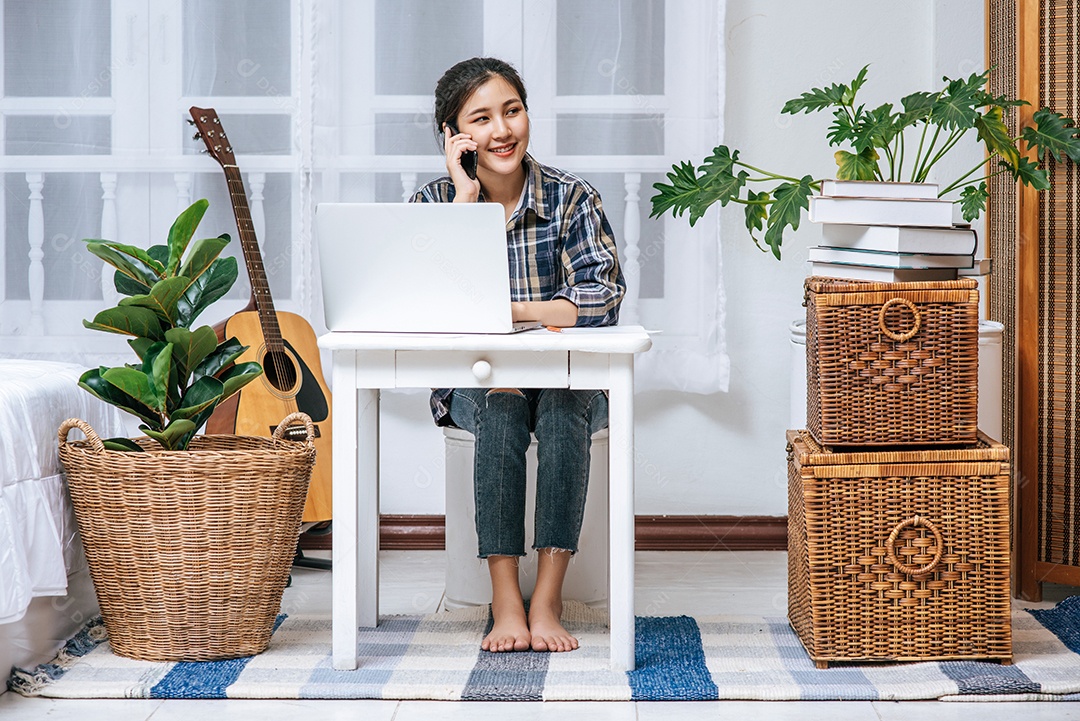 Mulher sentam-se à mesa e usam o telefone para coordenar.