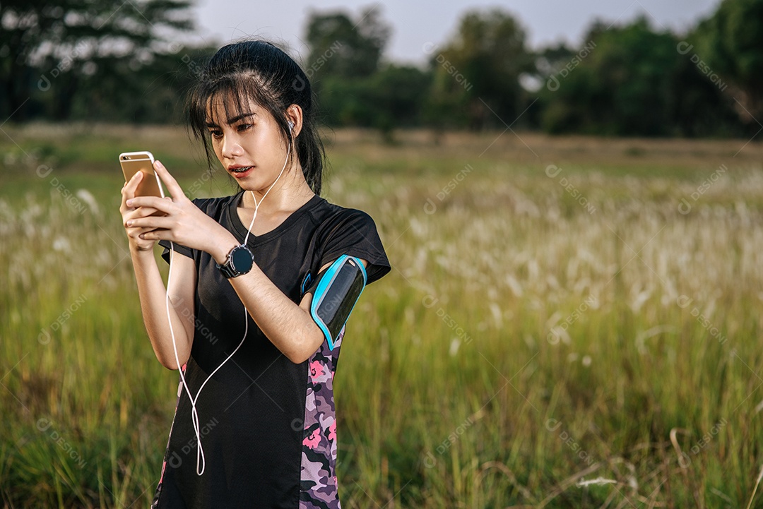 Woman is relaxed after exercising on the street and playing a smartphone.