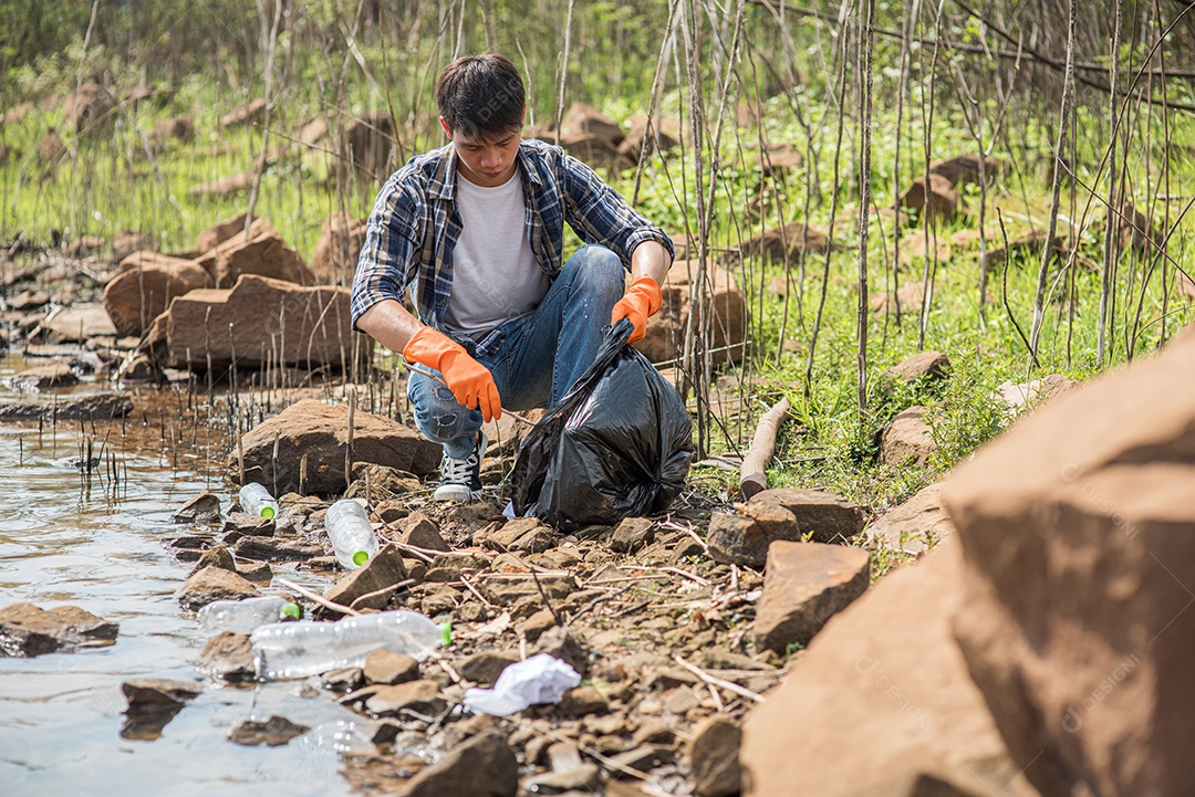 Homem usando luvas laranja coletando lixo em um saco preto