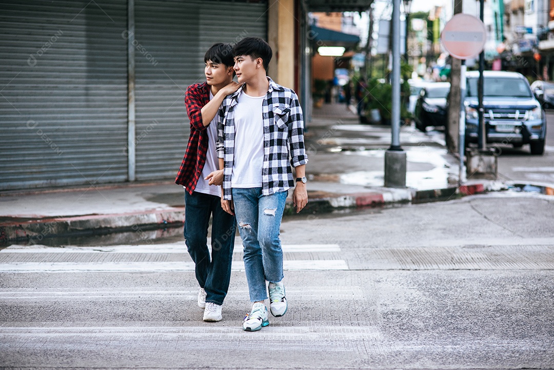 Dois jovens amorosos em camisas e andando na rua.