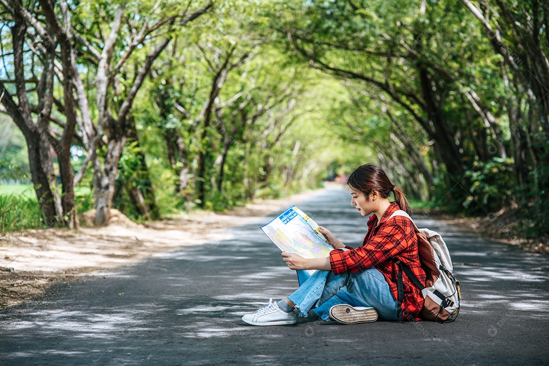 Turistas femininas sentam e olham para o mapa na estrada.