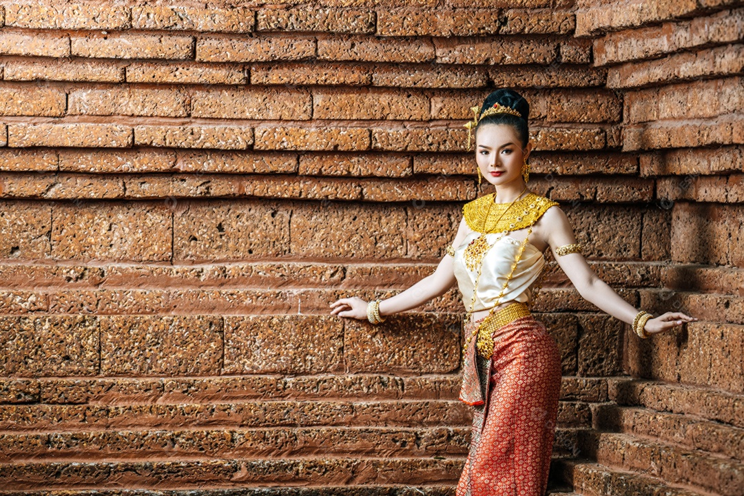 Retrato de mulher tailandesa encantadora em traje de vestido tradicional bonito, mulher vestindo vestido tailandês típico na parede de tijolos do sítio arqueológico ou fundo do templo tailandês, cultura de identidade da tailândia