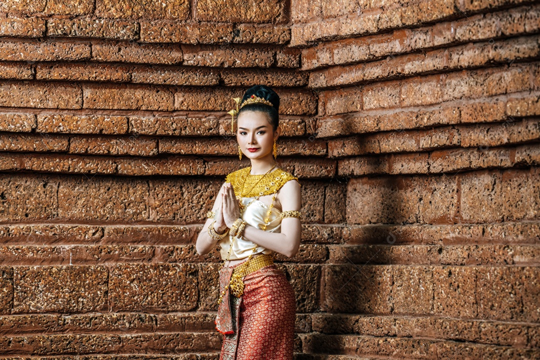 Retrato de mulher tailandesa encantadora em traje de vestido tradicional bonito, mulher vestindo vestido tailandês típico na parede de tijolos do sítio arqueológico ou fundo do templo tailandês, cultura de identidade da tailândia