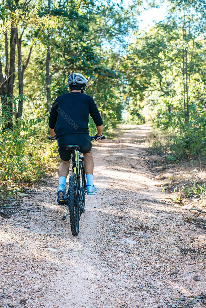 O homem andando de bicicleta em um caminho de montanha.