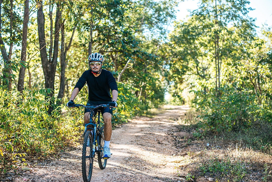 O homem andando de bicicleta em um caminho de montanha.