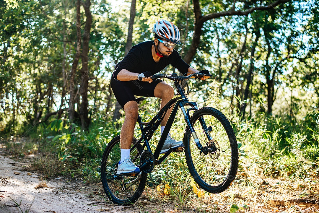 O homem andando de bicicleta em um caminho de montanha.